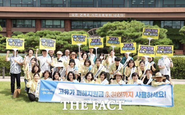 광명시 돌봄복지국 직원들이 30일 시청 잔디광장에서 고유가 피해지원금 소비 촉진 거리 캠페인 플랜카드를 들고 기념사진을 찍고 있다. /광명시