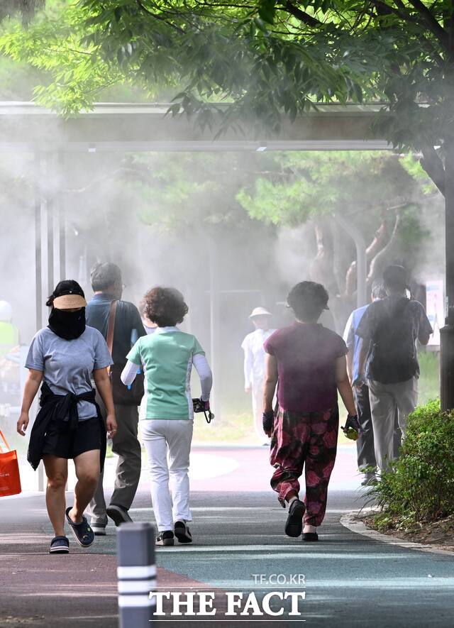 폭염에 지친 시민들이 안개형 냉각수가 뿌려지는 도로 위를 걷고 있다. /전남광주시