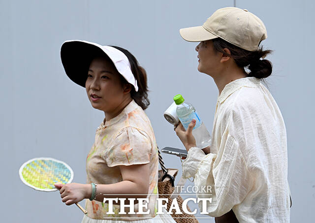부채와 선풍기 손에 든 관광객들.