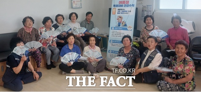 군위군 농업기술센터가 생활개선회 온열질환 예방요원들과 함께 마을회관을 찾아 농업인들에게 폭염 예방 수칙을 안내하고 기념 촬영을 하고 있다. /군위군