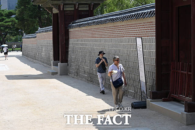외국인 관광객들이 나무 그늘에서 사진을 찍고 있다.
