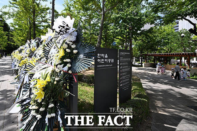 근조화환 뒤로 어린이들이 걸어가고 있다.