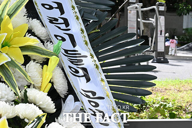 근조화환 뒤로 어린이들이 걸어가고 있다.