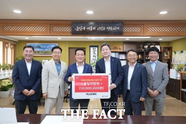 김인석 넥스트워터 대표(플래카드 오른쪽)가 13일 논산시청을 방문하고 백성현 논산시장(왼쪽)에게 1000만 원의 성금을 기탁하고 있다. /논산시
