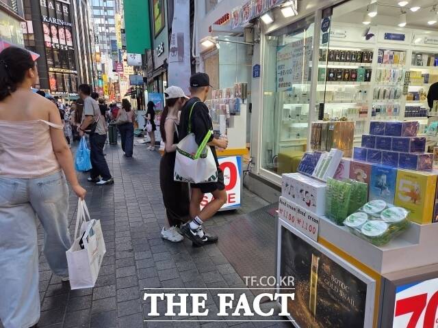 지난 12일 거리를 걷던 관광객이 서울 중구 명동거리에서 개문냉방 영업을 하고 있는 화장품 매장으로 들어가고 있다. 화장품 매장 직원 이모(40대) 씨는 
