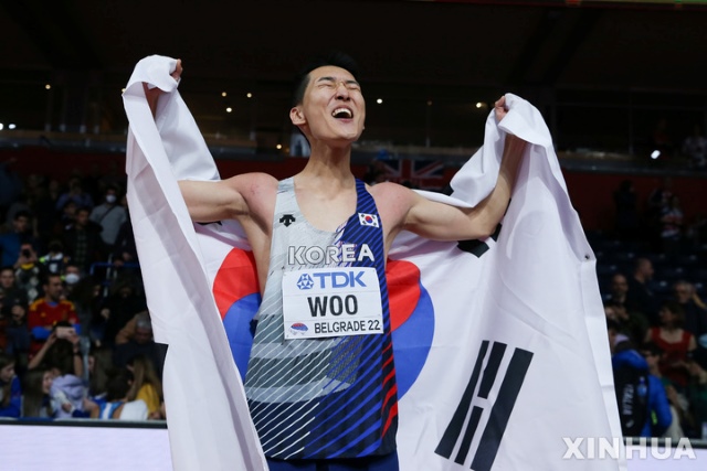 우상혁이 2022 세계실내육상선수권대회 남자 높이뛰기 결선에서 1위를 차지한 뒤 태극기를 몸에 두르고 환호하고 있다. / 신화 뉴시스