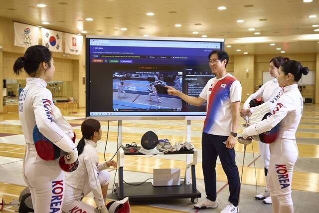 여자 펜싱 에페 국가대표팀 선수들과 함재만 코치가 SKT의 펜싱 AI 전력분석 시스템 'SKT-FAN'을 활용해 전력분석을 하고 있다. /SKT