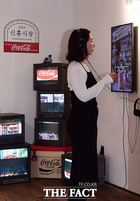 신흥시장 실내 전시 갤러리에서 상인들의 인터뷰 영상을 감상하는 관람객.