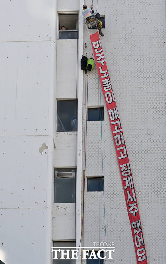 양규서 민주노총 공공운소노조 조직국장이 자신과 아내에 대한 징계·해고에 항의하며 7일 오전 서울 중구 경향신문사 빌딩 외벽에서 몸을 밧줄에 묶어 매달리는 고공 시위를 하고 있다. /박상민 기자