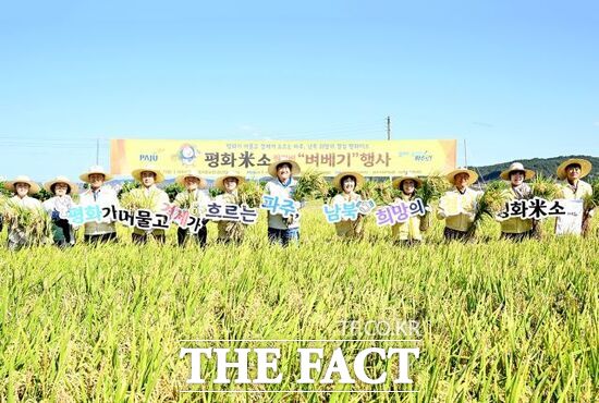 손배찬 경기 파주시장(왼쪽 입곱 번째를 비롯한 내외빈들이 지난 7일 장단면 작물실증시험포장에서 열린 평화미소 벼 베기 시연회에 참석, 평화미소를 알리기 위한 퍼포먼스를 하고 있다. /파주시