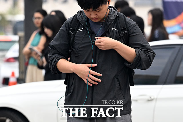 광화문 거리에 핀 수크령 너머로 출근길 시민들이 긴 소매의 옷차림을 하고 있다.