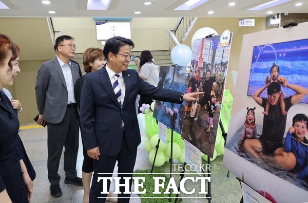 김찬술 대덕구청장(오른쪽)이 14일 구청 현관에 전시된 대덕구육아종합지원센터 ‘육아하는 아빠 사진 공모전’ 수상작들을 살펴보고 있다. /대덕구