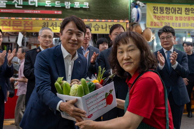 구본욱 KB손해보험 사장(왼쪽)이 서울 강서구 방신전통시장에서 열린 '추석맞이 전통시장 사랑나눔 행사'에 참석해 온누리상품권으로 구매한 명절 용품을 전달받고 있다. /KB손해보험