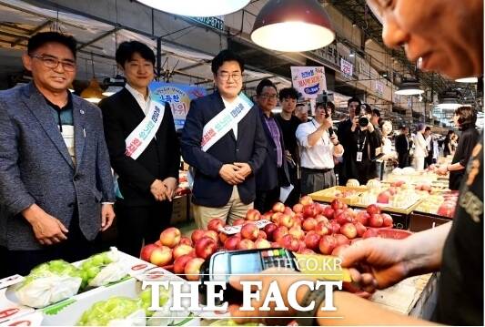 박찬대 인천시장이 21일 부평구 삼산농산물도매시장에서 상인들을 격려하며 인천이음카드로 물품을 구매하고 있다. /인천시