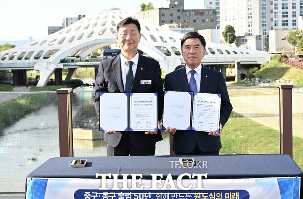 김제선 중구청장(왼쪽)과 황인호 동구청장(오른쪽)이 지난 22일 은행교에서 원도심을 하나의 생활·문화·경제권으로 연결하기 위한 '대전 원도심 르네상스 공동선언문'에 서명한 뒤 기념촬영을 하고 있다. /대전시 중구