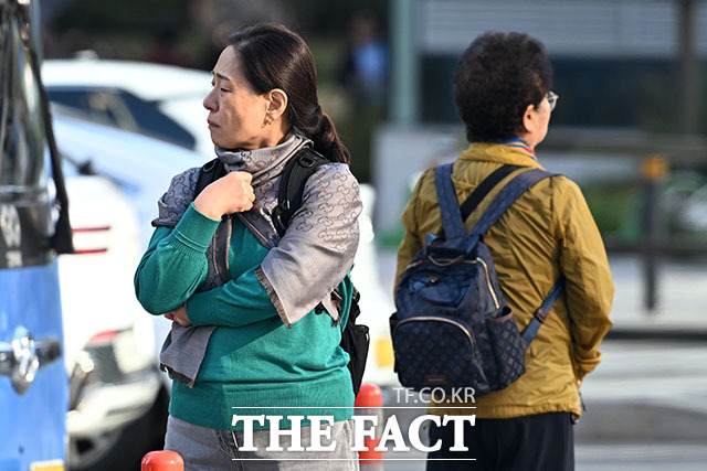 시민이 몸을 웅크린 채 발걸음을 옮기고 있다.