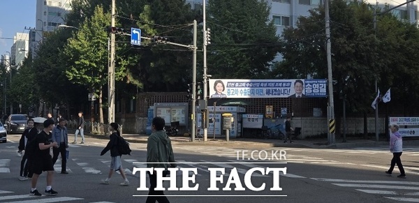5일 인천 연수구 옥련시장 입구 사거리에 송영길 국회의원과 정보현 인천시의원이 게시한 중고차 수출단지 이전, 해내겠다는 플래카드 앞으로 주민들이 횡단보도를 건너고 있다. /김형수 선임기자