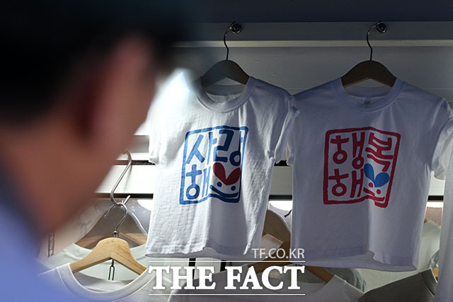 외국인 관광객이 한글이 새겨진 티셔츠를 구경하고 있다.