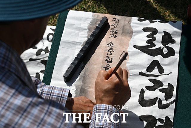 한글날 제정 100주년을 맞은 9일 오전 서울 종로구 광화문광장에서 열린 제17회 휘호대회에 참가한 한 어린이의 선글라스에 '열어가자 아름다운 바른한글'이 비치고 있다. /서예원 기자