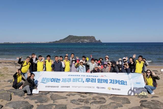 오비맥주 임직원들이 14일 제주 서귀포시 섭지코지 일대에서 지역 주민들과 함께 해변 정화 활동을 펼친 뒤 기념사진을 촬영하고 있다. /오비맥주