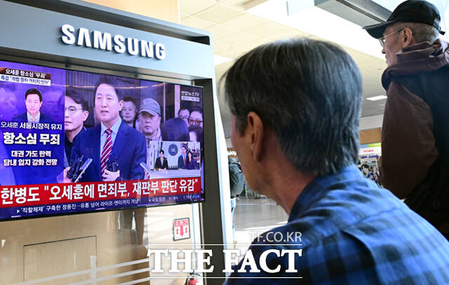 명태균 여론조사 대납 의혹을 받고 있는 오세훈 서울시장이 항소심에서 무죄를 선고 받은 가운데 23일 서울 용산구 서울역에서 시민들이 관련 뉴스를 시청하고 있다. /이새롬 기자
