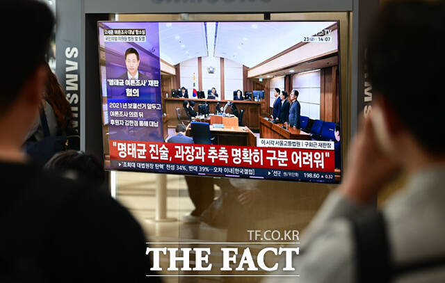 명태균 여론조사 대납 의혹을 받고 있는 오세훈 서울시장이 항소심에서 무죄를 선고 받은 가운데 23일 서울 용산구 서울역에서 시민들이 관련 뉴스를 시청하고 있다. /이새롬 기자