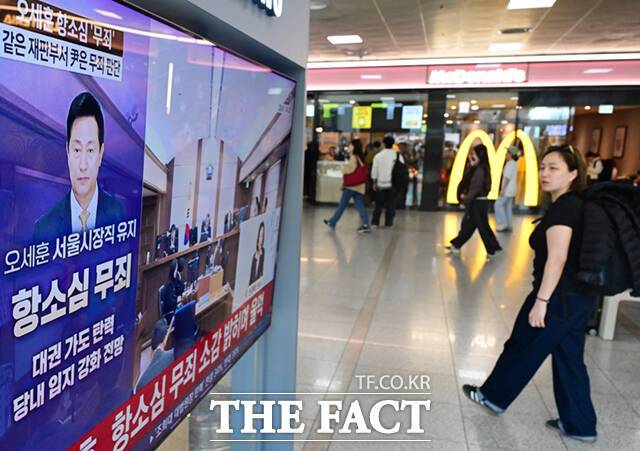 명태균 여론조사 대납 의혹을 받고 있는 오세훈 서울시장이 항소심에서 무죄를 선고 받은 가운데 23일 서울 용산구 서울역에서 시민들이 관련 뉴스를 시청하고 있다. /이새롬 기자