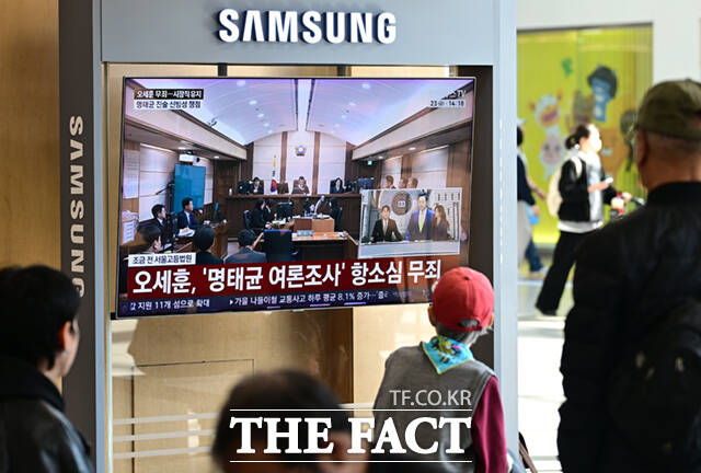 명태균 여론조사 대납 의혹을 받고 있는 오세훈 서울시장이 항소심에서 무죄를 선고 받은 가운데 23일 서울 용산구 서울역에서 시민들이 관련 뉴스를 시청하고 있다. /이새롬 기자