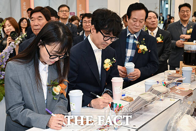 장항준 감독과 김은희 작가, 이환주 KB국민은행장이 참여 업체 관계자로부터 설명을 듣고 있다.