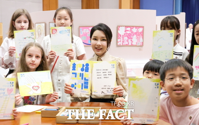 윤석열 전 대통령 부인 김건희 여사가 지난해 5월 21일 청와대 춘추관에서 열린 희망을 그리는 아이들: 우크라이나 아동 그림전을 찾아 아이들과 메시지 종이를 다 같이 들고 기념촬영 하고 있다. 이번 그림전은 우크라이나 대통령 영부인 젤렌스카 여사의 강력한 요청으로 ‘생명 존중과 ‘세계 평화를 위해 김건희 여사가 기획했다. /뉴시스