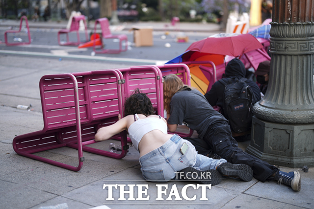 8일(현지시간) 미 캘리포니아주 로스앤젤레스 도심 메트로폴리탄 구치소 인근 101번 고속도로에서 이민세관단속국(ICE)의 불법 이민자 단속 및 체포에 항의하는 시위대가 의자 뒤로 몸을 숨기고 있다. /로스엔젤레스=AP.뉴시스