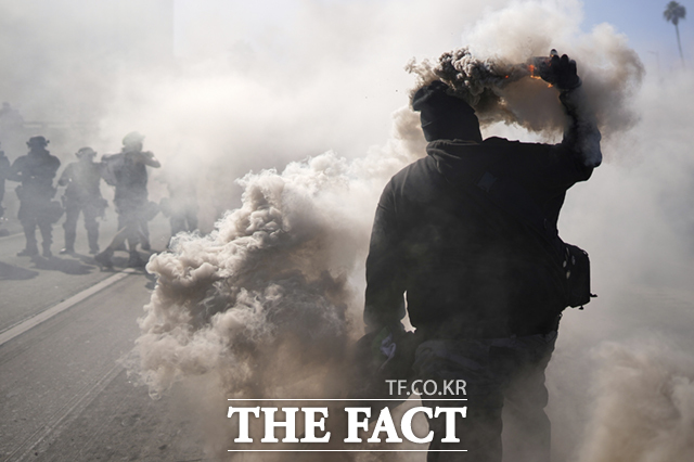 8일(현지시간) 미 캘리포니아주 로스앤젤레스 도심 메트로폴리탄 구치소 인근 101번 고속도로에서 이민세관단속국(ICE)의 불법 이민자 단속 및 체포에 항의하는 시위 참가자가 경찰을 향해 연막탄을 던지고 있다. /로스엔젤레스=AP.뉴시스