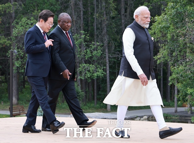 이재명 대통령이 17일(현지 시간) 캐나다 앨버타주 카나나스키스 G7 정상회의장에서 열린 51차 G7 및 초청국 정상 단체사진 촬영에 입장하며 시릴 라마포사 남아공 대통령과 대화를 나누고 있다. /뉴시스