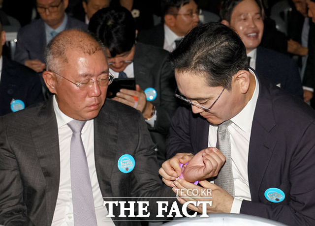 임명식을 앞두고 이재용 삼성전자 회장이 정의선 현대차그룹 회장에게 야광팔찌를 채워주고 있다. /뉴시스