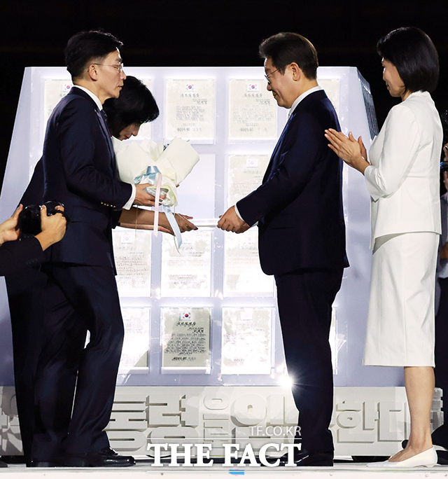 이재명 대통령이 15일 서울 세종대로 광화문광장에서 열린 제21대 대통령 국민임명식 광복 80년, 국민주권으로 미래를 세우다 행사에서 이국종 국군대전병원장, 이연수 NC AI 대표로부터 임명장을 받고 있다. /뉴시스