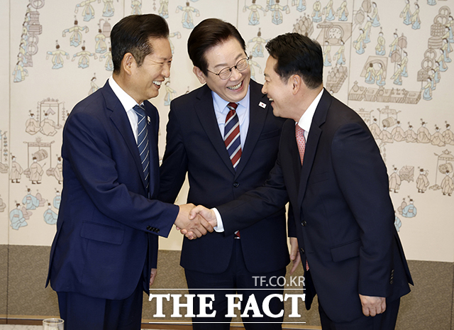 이재명 대통령이 8일 오후 서울 용산구 대통령실 청사에서 열린 여야 지도부 오찬 회동에 앞서 정청래 더불어민주당 대표(왼쪽)와 장동혁 국민의힘 대표의 악수 모습을 보며 밝게 웃고 있다. /뉴시스