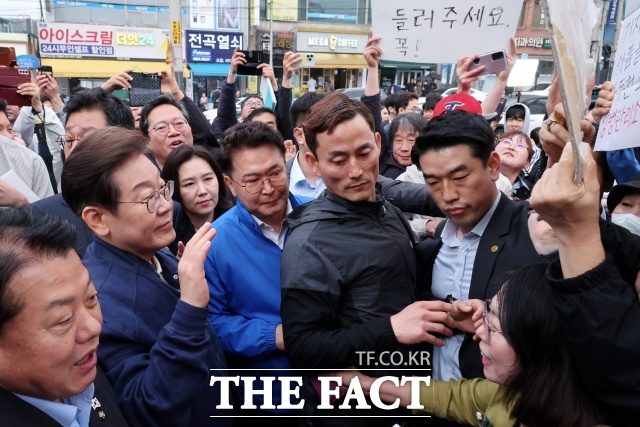 경청투어에 나선 당시 이재명 더불어민주당 대선후보가 지난 5월1일 오후 경기도 연천군 전곡읍 인근에서 시민들과 인사를 나누다 동두천 옛 성병 관리소 철거저지를 위한 공동대책위원회(공대위)의 소요산 옛 성병관리소 돌려주세요가 적힌 피켓을 보고 있는 모습. /뉴시스