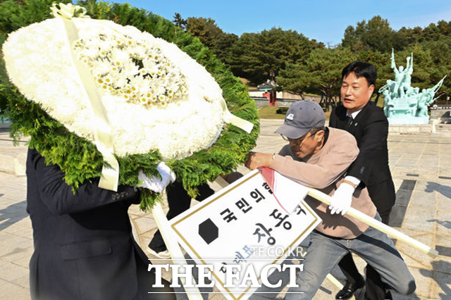 한 시민이 장 대표의 화환을 치우다 묘역 관계자들과 실랑이를 하고 있다. /광주=뉴시스