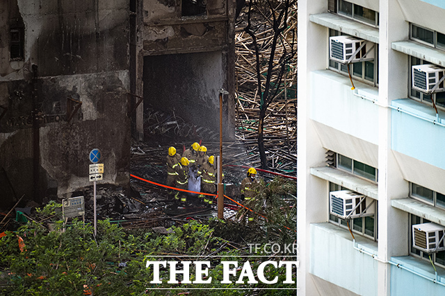 28일(현지 시간) 홍콩 타이포 지구 웡 푹 코트 아파트 단지 화재 현장에서 소방관들이 희생자 시신을 수습하고 있다. 화재 진화가 종료된 가운데 사망자 수는 94명으로 늘어났으며 구조대는 실종자 수색을 이어가고 있다. /홍콩=AP.뉴시스