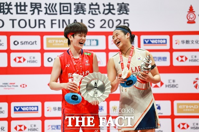 96분의 접전을 펼친 중국의 왕즈이(왼쪽)와 트로피를 들고 밝게 웃고 있는 안세영./신화.뉴시스
