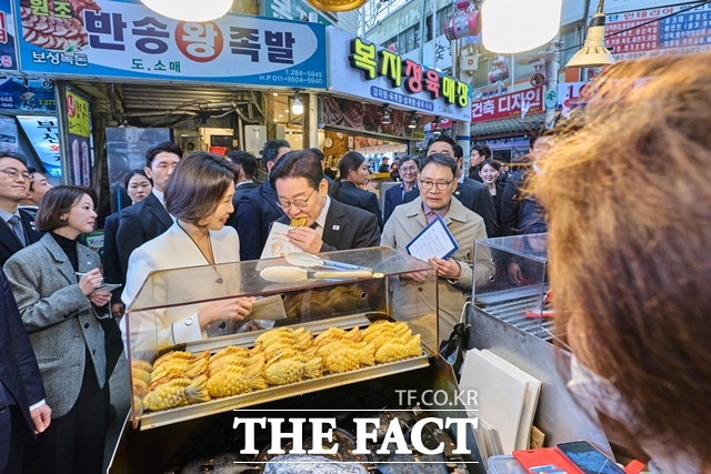 이재명 대통령이 15일 영부인 김혜경 여사와 함께 경남 창원시 반송시장을 깜짝 방문해 붕어빵을 맛보고 있다. /뉴시스