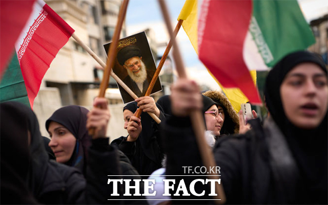 한 여성이 전 이란 최고 지도자 아야톨라 알리 하메네이의 초상화를 들고 있다.