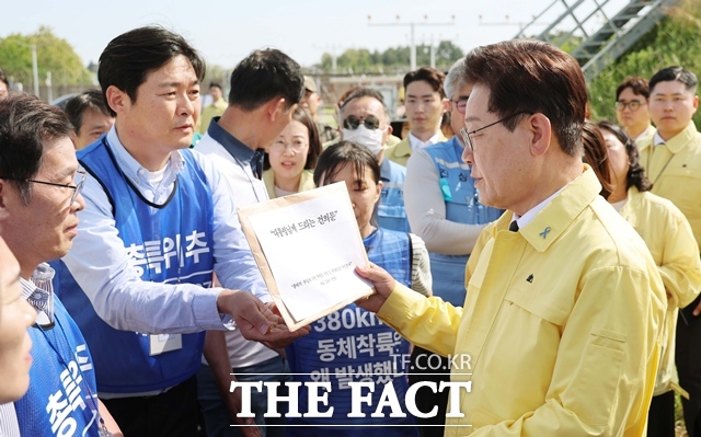 이재명 대통령이 18일 전남 무안공항 여객기 참사 유해 수습 현장을 찾아 유가족에게 건의문을 받고 있다. /뉴시스