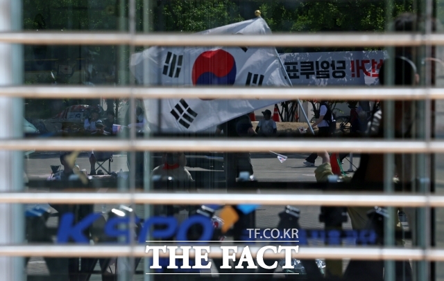 18일 오전 6·3 지방선거 투표용지 부족 사태를 규탄하는 시위가 14일째 열리고 있는 서울 송파구 올림픽공원 핸드볼경기장 출입문 유리에 시위대 모습이 비치고 있다. /뉴시스