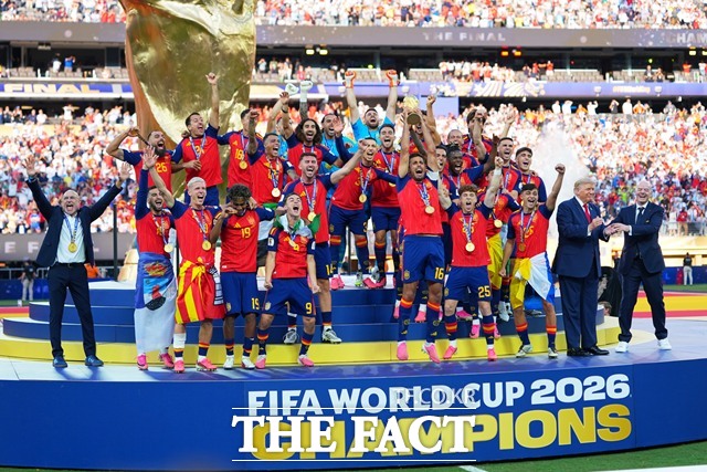 20일 2026 북중미 월드컵 결승에서 아르헨티나를 1-0으로 꺾고 16년 만에 우승을 차지한 스페인 선수들이 시상대에서 환호하는 무대에서 함께 사진을 찍던 도널드 트럼프 대통령이 잔니 인판티노 FIFA 회장으로부터 이석을 요청받고 있다./뉴저지=AP.뉴시스